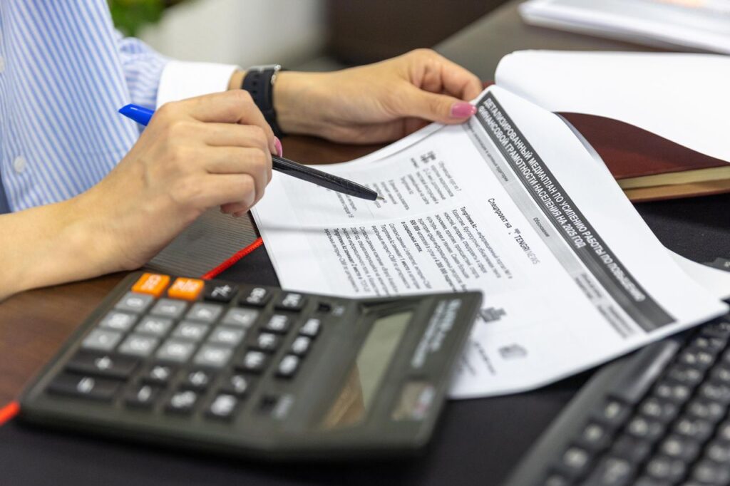 pexels photo 33175651 33175651 Close-up of a person analyzing financial documents using a calculator and pen.