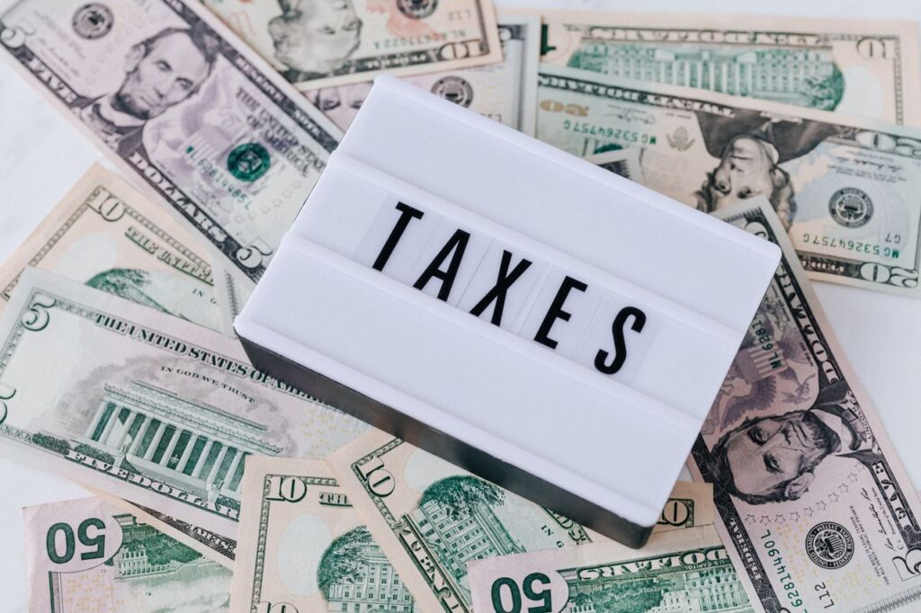 pexels photo 4386367 4386367 From above of white retro lightbox with TAXES inscription placed on pile of USA dollar bills on white surface